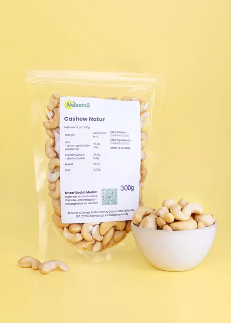 Cashew Natur im Beutel, daneben eine Schale Cashewkerne