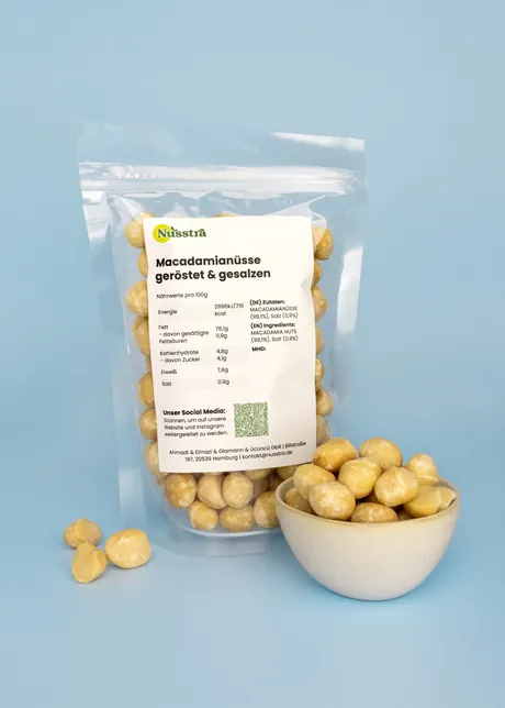 Macadamianüsse geröstet und gesalzen im Beutel, daneben eine Schale Macadamias